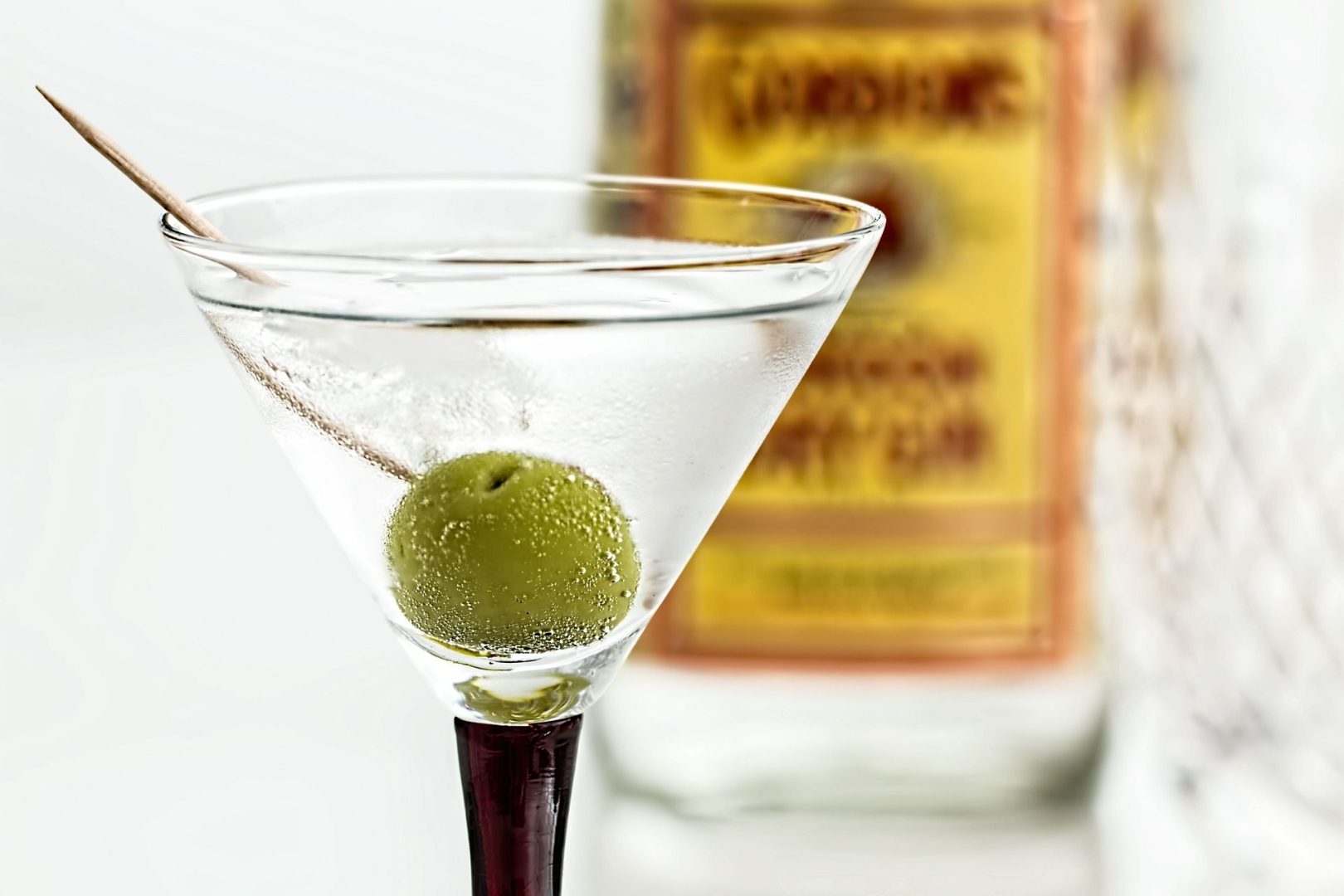 A class of Martini cocktail with a Gin bottle in the background
